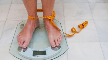 CNE3JY Mature woman weighing herself.