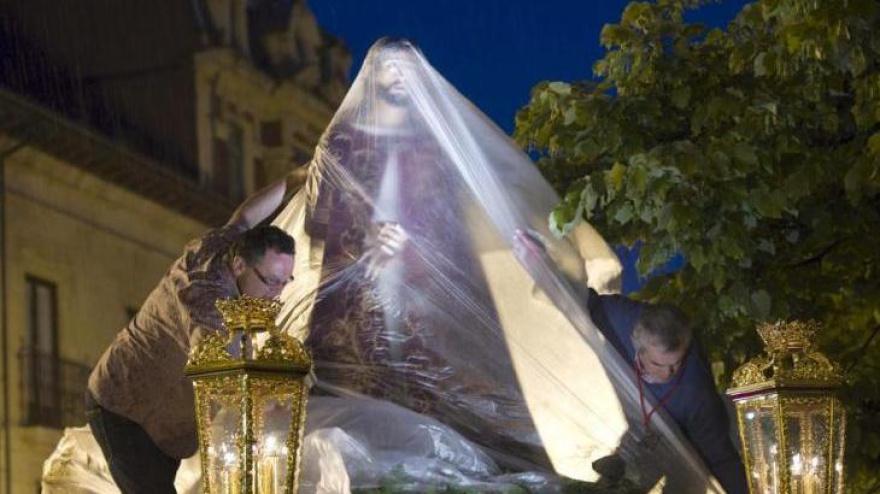 El paso de Jesús Cautivo, cubierto con plásticos, en la Plaza de la Catedral de Oviedo, bajo un intensa lluvia