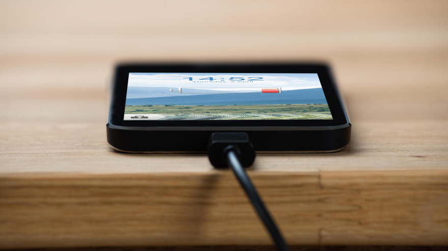 Un smartphone sin batería conectado a un cargador sobre una mesa de madera