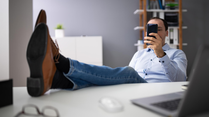 Un hombre perezoso utiliza su teléfono móvil en lugar de trabajar