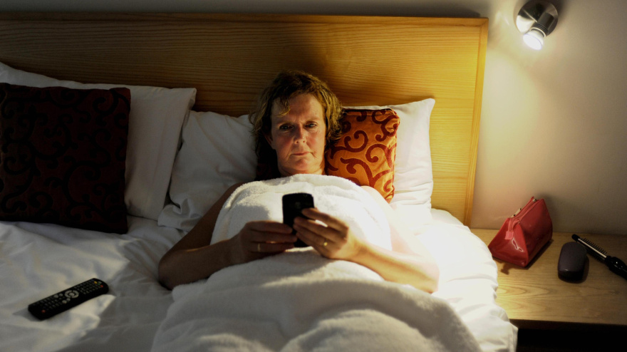 Una mujer utiliza su teléfono móvil en la cama antes de irse a dormir