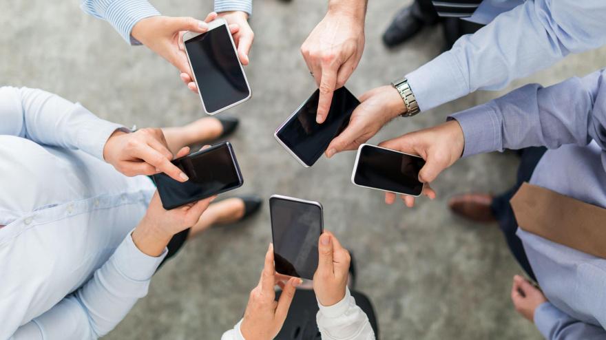 Un grupo de amigos sujetando sus teléfonos móviles