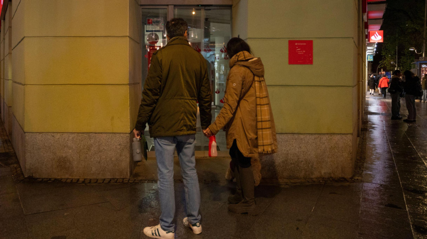 Los peatones pasan junto a la sucursal del banco comercial multinacional español y de servicios financieros Santander durante la noche.