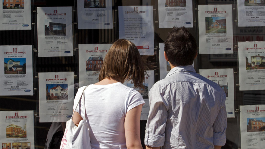 Una pareja mirando carteles de venta de pisos en una inmobiliaria