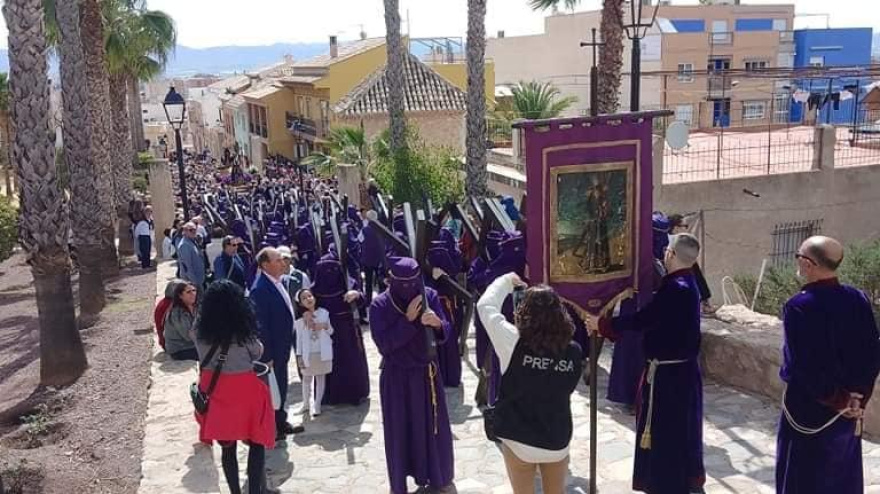 Penitentes con el rostro cubierto y la cruz suben la cuesta del Calvario en el Vía Crucis de Lorca