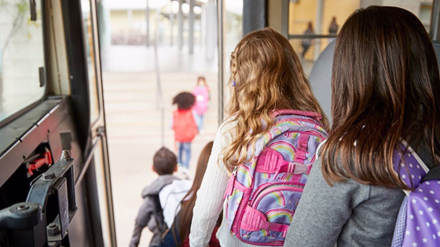 Two girls waiting behind their friends to get off school bus