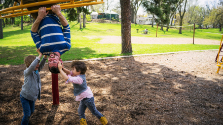 Padre y dos hijos jugando en un patio de recreo