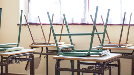 Fotografía de algunas sillas sobre mesas en un aula de una escuela primaria.