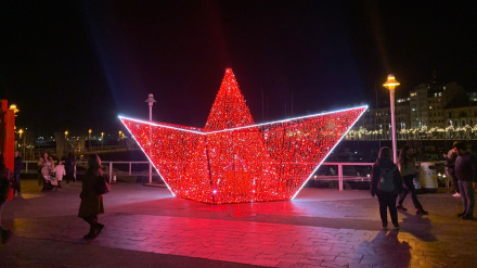 Barco de papel iluminado junto a 'Las Letronas' del Puerto Deportivo de Gijón, durante la Navidad de 2024