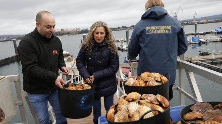 Martina Aneiros ayuda a Jorge López con un capacho de vieiras
