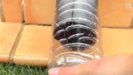 La joven poniendo una botella vacía en un canalón