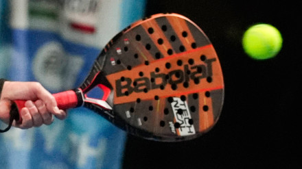 Detalle de una raqueta de pádel golpeando la pelota durante un partido