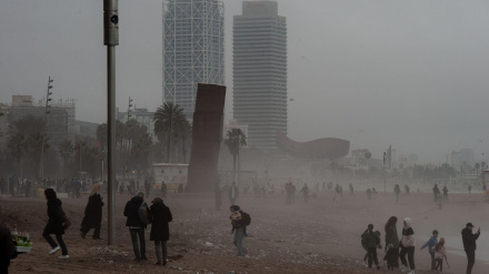 La gente camina por la playa de la Barceloneta en Barcelona en medio de la bruma