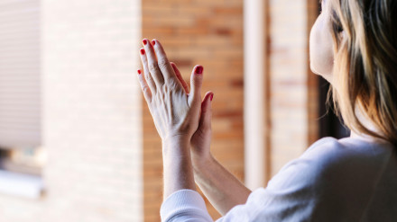 Una mujer aplaude desde la ventana de su casa en la cuarentena del estado de alarma por el coronavirus