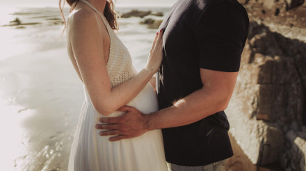 Un hombre sostiene la barriga de su bella pareja embarazada en una playa del País Vasco
