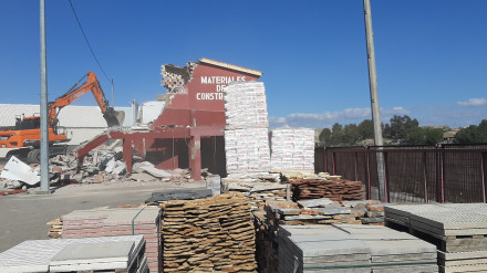 Una pala retroexcavadora derriba construcciones para ampliar la carretera junto al río, en Lorca