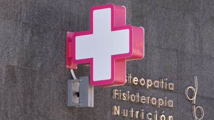 Cruz blanca y fucsia que identifica una clínica de fisioterapia