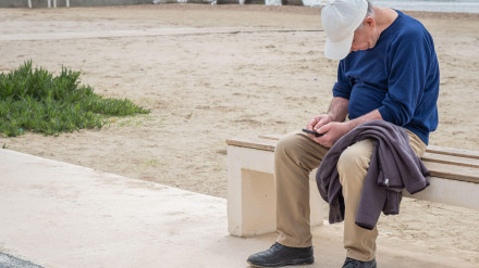 Un hombre jubilado solitario navegando en su teléfono móvil