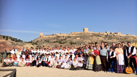 El grupo Coros y Danzas de Lorca posa ante el castillo de la ciudad con trajes tradicionales