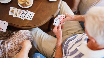 Un anciano juega a las cartas en un local social