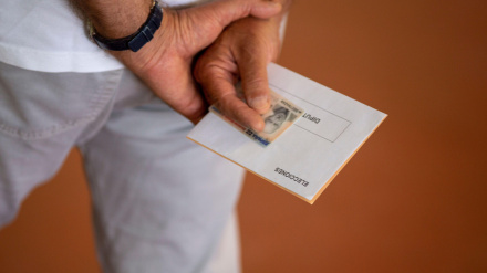 Un hombre sostiene su DNI antes de votar