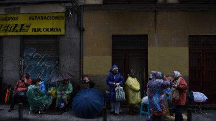 Fieles católicos usan paraguas en una calle de Madrid mientras esperan, algunos hasta quince días, para besar los pies de el Cristo de Medinaceli.