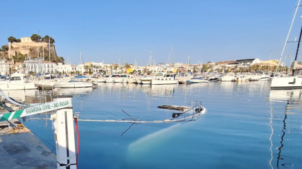 Restos de las embarcaciones hundidas tras el incendio en el puerto de Dénia, aún visibles en la superficie al amanecer