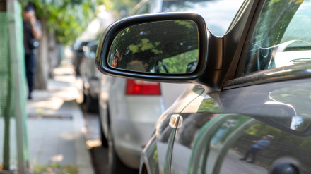 Espejo retrovisor de un automóvil estacionado cerca de la acera al costado de la calle