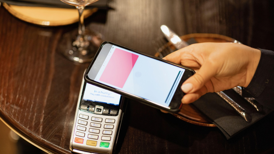 Una persona irreconocible que usa un teléfono móvil para pagar una comida.