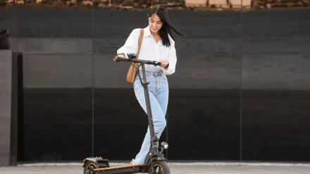 Joven empresaria montando patinete eléctrico al aire libre