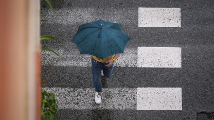 Un hombre se protege de la lluvia en La Foia, en Elche
