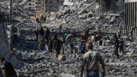 Palestinos caminan por una calle entre los escombros de los edificios destruidos durante el alto el fuego entre Israel y Hamás