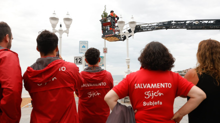 Personal de Salvamento colocan un ramo de laurel en la playa de San Lorenzo de Gijón
