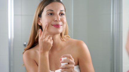 Mujer aplicando crema con retinol anti-signos de la piel en el baño