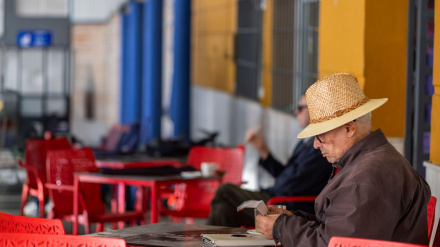 Un jubilado con sombrero de paja relajándose en una cafetería de Ronda