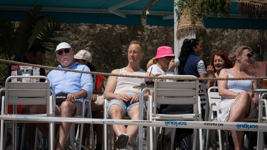 Varias personas toman algo en la terraza de un bar en el paseo marítimo de la playa de la Barceloneta
