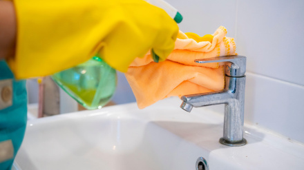 Empleada del hogar limpiando el grifo de un baño