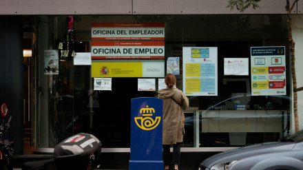 Mujer frente a una oficina de empleo (SEPE) leyendo los carteles expuestos en el escaparate en Madrid