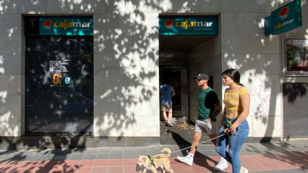 Dos personas pasan por delante de una oficina de Cajamar
