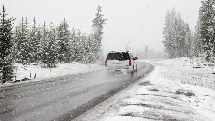 Un coche circula por una carretera nevada