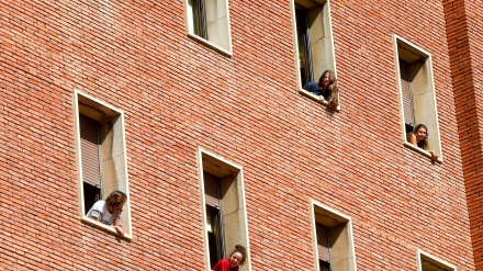 Varios estudiantes en las ventanas de un colegio mayor