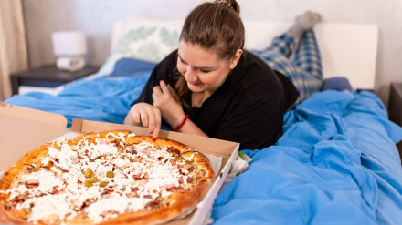 Una chica come una pizza en la cama