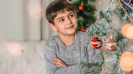 Un niño junto al árbol de Navidad
