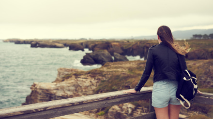 Mujer joven contemplando la playa de las Catedrales (Aguasantas) con marea alta en Ribadeo