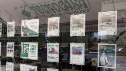 Varios carteles de pisos en venta en una oficina de Tecnocasa