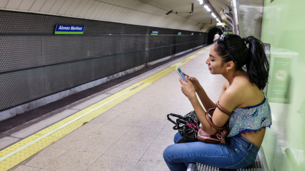 Una joven espera el metro mirando su móvil en Madrid