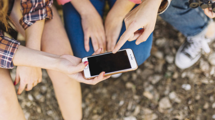 Imagen de archivo de jóvenes usando teléfono móvil