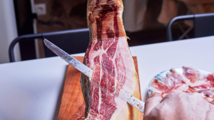 Una mano de un cortador de jamón profesional cortando un jamón ibérico en finas lonchas listo para comer