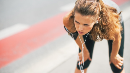 Portrait of tired fitness young woman outdoors in the city catching breathe