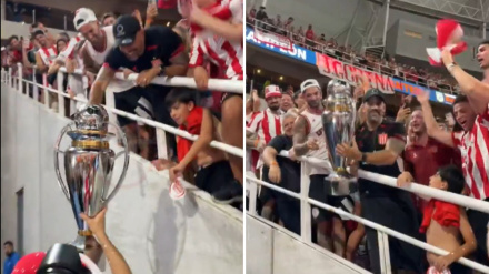 Juan Sebastián Verón levanta la copa de campeón en la grada al estar sancionado.